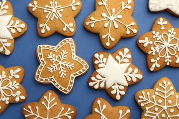 Tasty star shaped Christmas cookies with icing on blue background, flat lay