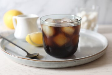 Refreshing iced coffee in glass and spoon on white wooden table, closeup