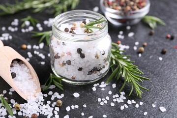 Salt with fresh rosemary and peppercorns on dark grey textured table