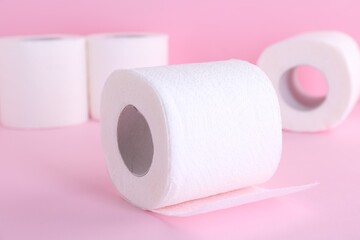 Soft toilet paper rolls on pink background, closeup