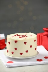 Bento cake with red cream hearts and gift boxes on grey table. St. Valentine's day surprise