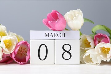 International Women's day - 8th of March. Wooden block calendar and beautiful flowers on white table