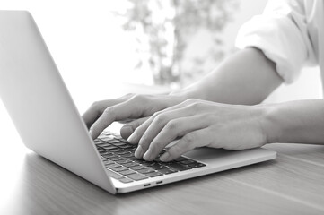 ノートパソコンで仕事をしている男性（白黒）