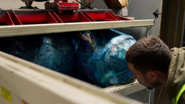 Special garbage compactor machine presses large garbage bag for waste disposal at waste recycling station