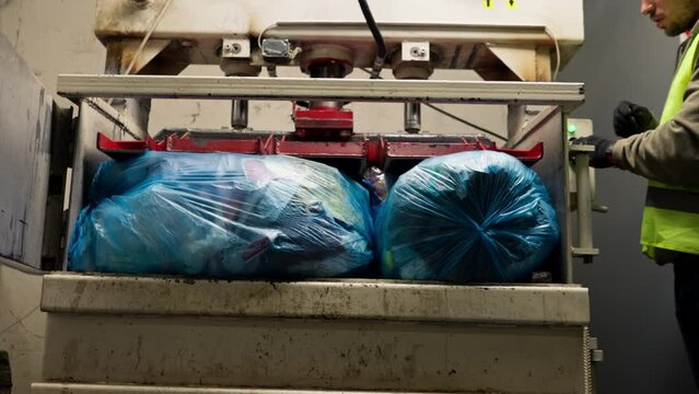 Special garbage compactor machine presses large garbage bag for waste disposal at waste recycling station