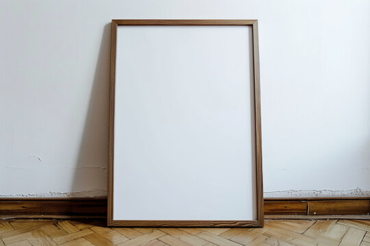 photo of a large blank frame leaning against a white wall. Frame is wood. resting on wooden parquet, close up, photo taken straight ahead