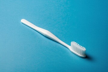 A white toothbrush rests delicately on a vibrant blue background. Soft bristle brush denotes care and hygiene while blue reflects tranquility and freshness. - obrazy, fototapety, plakaty