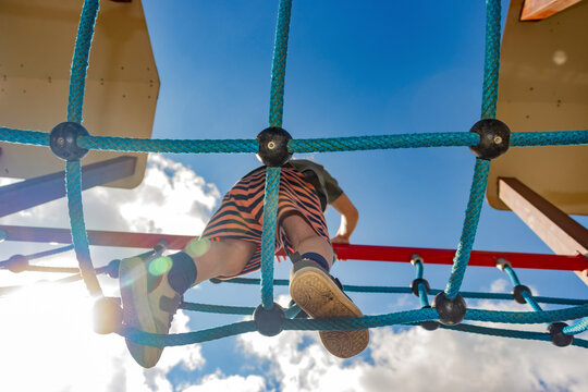 A little boy walks on a rope bridge