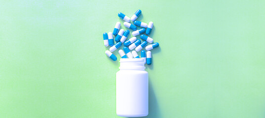 Medicine capsules and pill bottles isolated on colored background,Pills spilling out of pill bottle and isolated on blue. Top view with copy space. Medicine concept