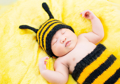 baby in bee costume,isolated on white, happy baby caucasian boy in bee costume lies with hands in mouth