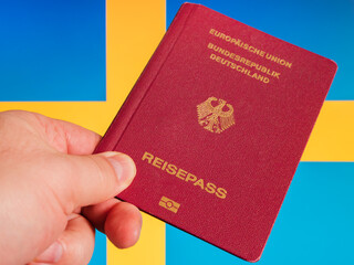 German Passport Held in Hand Against Blue and Yellow Background