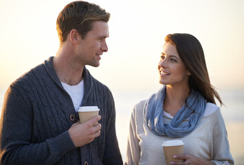 Couple, coffee and sunset by ocean on vacation, walking and conversation in summer at beach. Man, woman and drink with tea cup with smile, bonding and happy for memory on holiday by sea in Australia