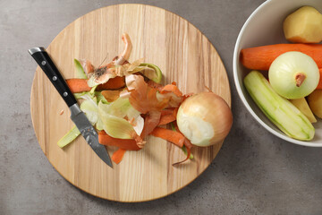 Peels of fresh vegetables and knife on grey table, flat lay