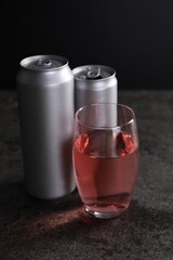 Energy drink in glass and aluminium cans on grey table