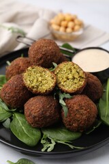 Delicious falafel balls, herbs and sauce on table