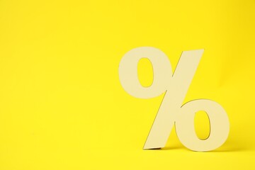 Wooden percent sign on yellow background. Space for text