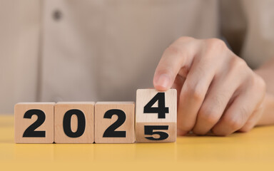 Business plan and countdown to 2025, The hand changing 2024 to 2025 on wooden cubes, Starting new business target strategy concept, Prepare to enter the new year.