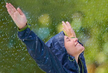 Woman, rain and freedom with a smile from wet climate, water and weather outdoor in a park. Happy,...