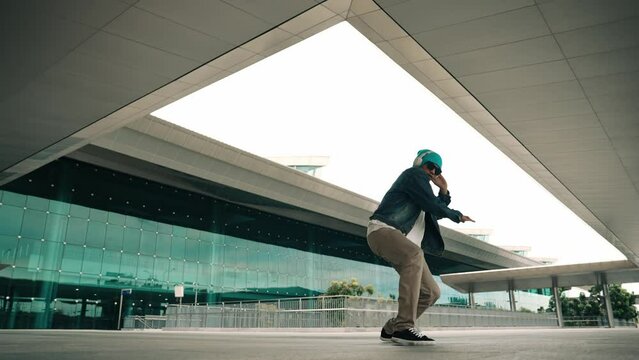 Happy hipster practice b boy dance with stylish cloth at building. Skilled street dancer enjoy show footstep performance. Modern lifestyle, break dancing. Slow motion. Outdoor sport 2024. Sprightly.