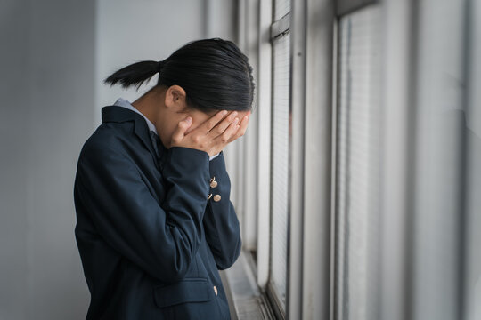 教室の窓際で泣く高校生・中学生・小学生の女の子（号泣・いじめ・孤独）
