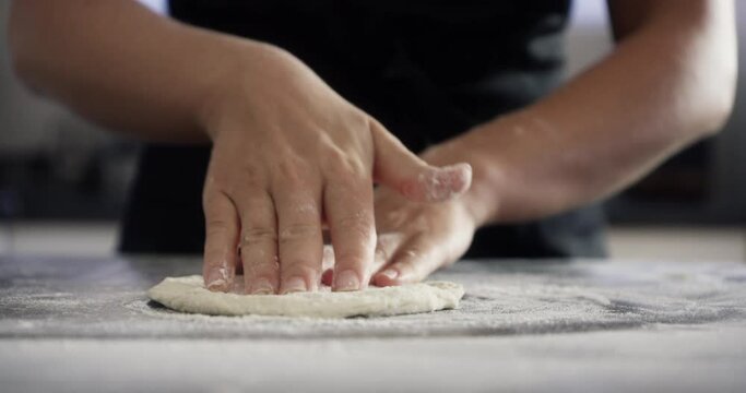 Chef, hands and dough with wheat on kitchen table for baking, cooking or pizza process in apartment. Person, bakery and pastry for recipe, handmade cake or bread with flour or preparation in home