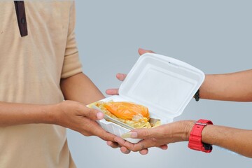 Close up of hand giving food and other hand receiving it on gray background. Concept of breaking...