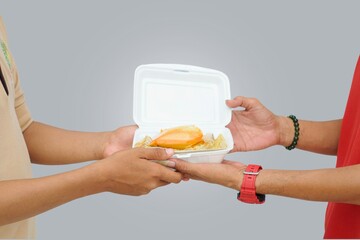 Close up of hand giving food and other hand receiving it on gray background. Concept of breaking...