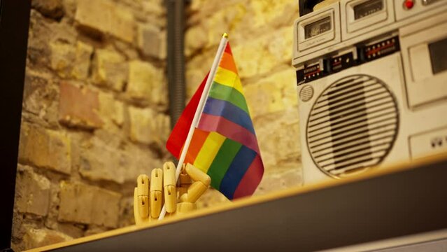 Close-up of a stand in the form of a wooden hand holding a rainbow small flag of representatives of LGBT positive attitudes towards minorities