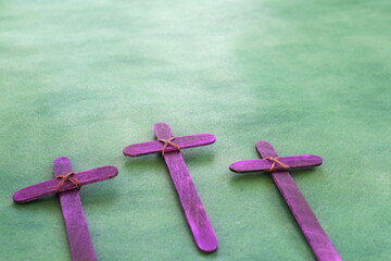 Selective focus of three purple wooden cross in green background. Holy week and lent season...