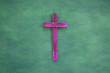 Purple wooden cross flat lay in green background. Holy week and lent season celebration concept.