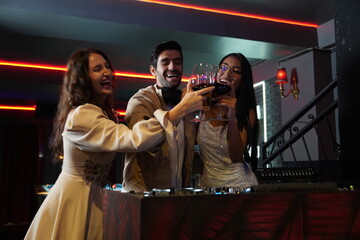 man working disc jockey Dj mixing songs in bar party.Two Asian and Caucasian friends dancing having fun nightlife dancing with DJ man and drinking wine together in disco club.Entertainment concept.