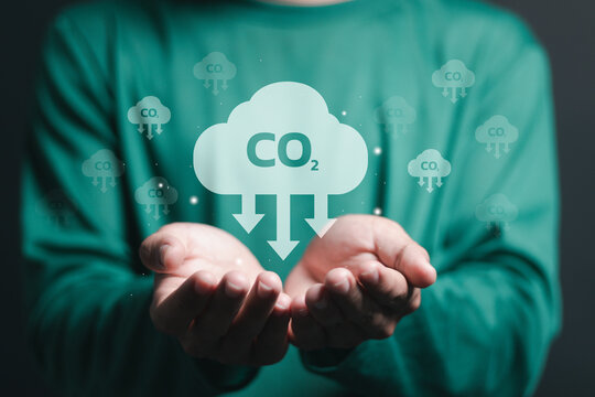 Reduce CO2 Emissions. Climate Change To Limit Global Warming And Sustainable Development And Green Business. Person Holding Carbon Reduction Icon On Virtual Screen.