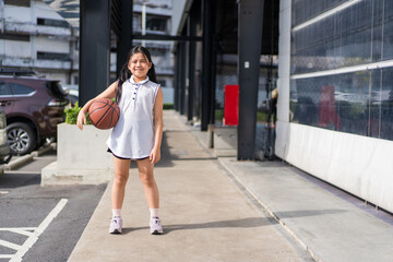 basketball and asian child or kid girl standing holding to playing and smile training to learning ball at sports stadium school or basketball court for exercise on sport day and holiday with copyspace