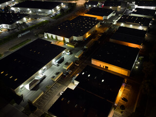 Nondescript warehouses and office buildings of an industrial business park are shown from an overhead view at night.