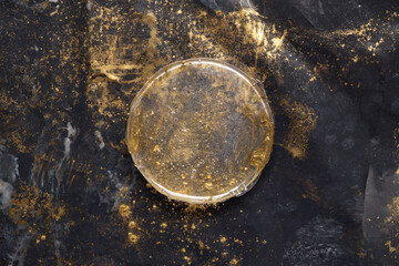 Figura circular de resina epóxica sobre Plástico negro con pigmento dorado regado