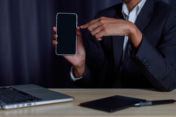 Chatbot Chat with AI Businessman's hands sitting in front of computer and using smart mobile phone to do business.