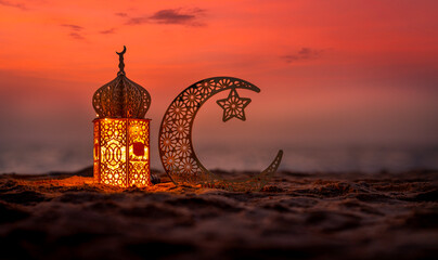 Traditional lantern lamp with crescent moon on the beach during sunset, Ramadan Kareem and Eid Mubarak greeting banner image