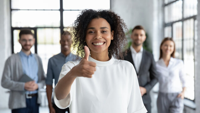 Company staff guaranteeing best service. Smiling businesswoman looking at camera giving thumbs up, proud of good results. HR manager satisfied with new recruits. Young lady happy about career choice