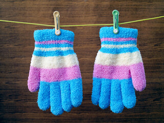 colourful children winter gloves with clothespin hanging on rope clothes line