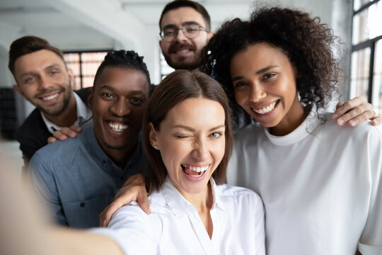 Start-up founder with employees taking funny group selfie after successful business meeting, or during break at work. Diverse team of friendly work buddies capturing happy moment of corporate life