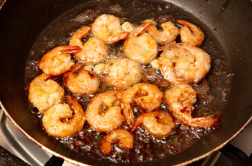 Shrimp are fried in a frying pan in oil