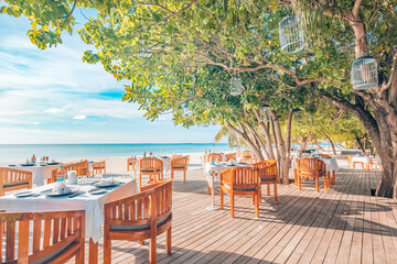 Outdoor restaurant beach bar. Luxury table setting tropical beach restaurant. Sunset light trees...