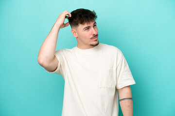 Young caucasian handsome man isolated on blue background having doubts while scratching head