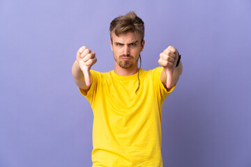 Young handsome blonde man isolated on purple background showing thumb down with two hands