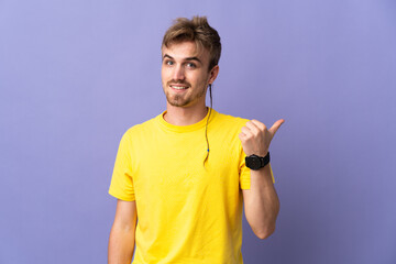 Young handsome blonde man isolated on purple background pointing to the side to present a product