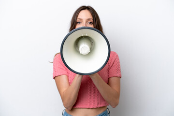 Young caucasian woman isolated on white background shouting through a megaphone to announce...