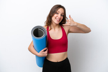 Young sport caucasian woman going to yoga classes while holding a mat isolated on white background making phone gesture. Call me back sign