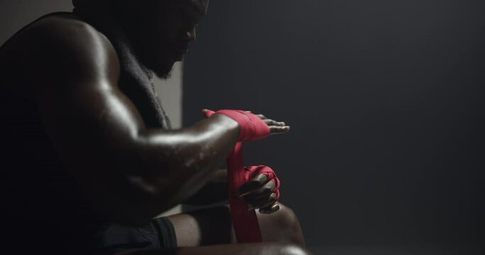 Black man, boxer and wrapping hands in locker room for competition or training at night, club or gym. African male person, athlete or fighter gloves with bandage for preparation, MMA or self defense
