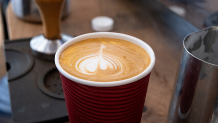 Close up of delicious golden flat white coffee with latte art in tulip heart shape in local coffee...