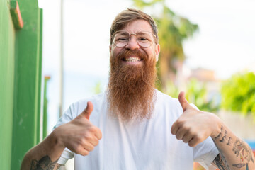Redhead man with beard With glasses and with thumb up